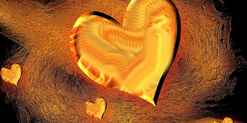 ein goldenes Herz mit gelben und roten Spuren liegt auf einem hellbraunen und dunkelbraunen sand