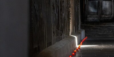 Foto: Pfarrmedien Österreich / T. Ohnewein rote Lichterspur im Dunkeln entlang von Grabsteinen