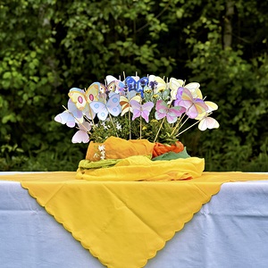 Papierschmetterlinge, die in Blumentopf zwischen Blumen stecken