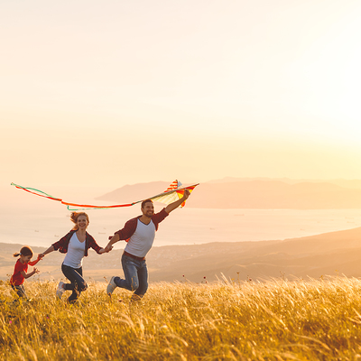 Happy family father,  mother and child daughter launch a kite on nature at sunset