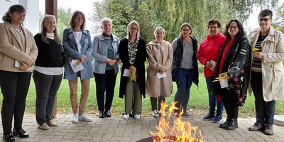 Frauen stehen im Halbkreis um ein Feuer