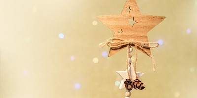 Ein Stern aus Holz der an einer Schnur hängt mit golden leuchtendem Hintergrund