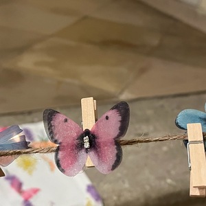 Schmetterling, der mit Kluppe befestigt an Schnur hängt